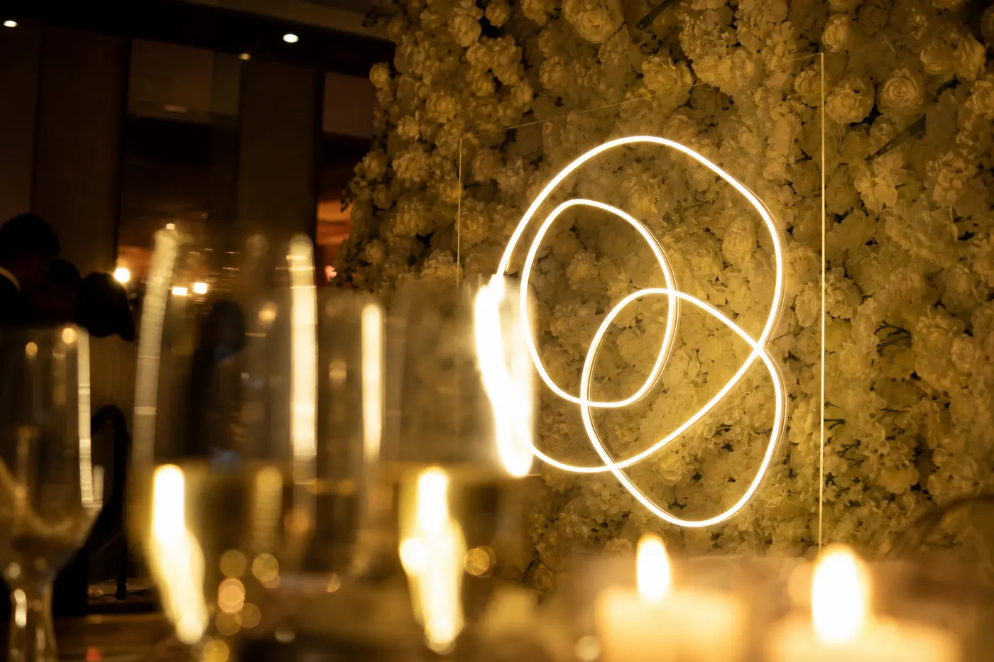 Warm white abstract rings LED neon with blurred glasses and candles at a wedding reception